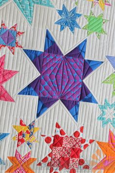 a quilted wall hanging with colorful stars on it