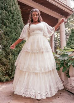 a woman in a white dress is standing on a porch with her arms outstretched and hands out