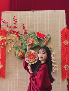 a woman holding a plate in front of a wall decorated with red and green decorations