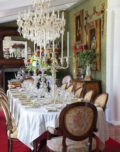 a formal dining room with chandelier and table set for six people, all dressed in white