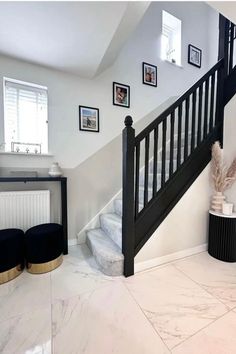 there is a black and white staircase in the house with pictures on the wall above it