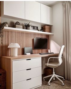 a desk with a computer on top of it next to a lamp and some drawers