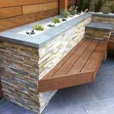 a wooden bench sitting next to a wall with succulents growing on it