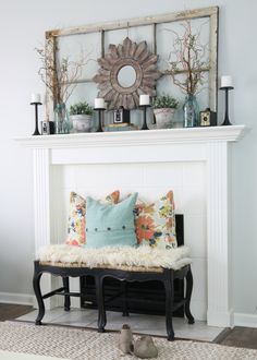 a living room with a white fireplace and pillows