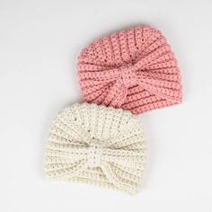 two crocheted hats with a bow on the top one is pink and white