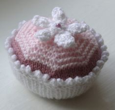 a crocheted cupcake sitting on top of a white table next to a wall