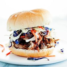 a pulled pork sandwich with cole slaw on a white plate