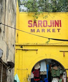 an old yellow building with clothes hanging on the side and a sign that says sarojni market