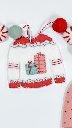 an ornament hanging from a string on a white surface with red and green decorations