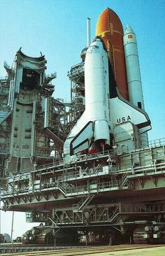 the space shuttle is on display in front of an industrial building with stairs leading up to it