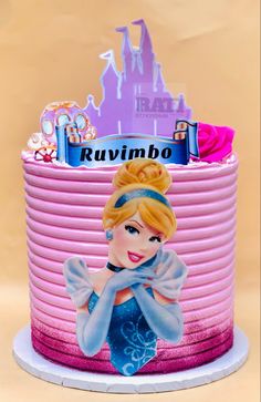 a pink cake with a princess figure on it's top and the words kuvimbo above it