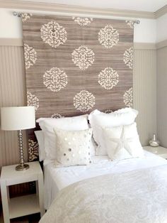 a bed with white pillows and decorative wallpaper on the headboard in a bedroom