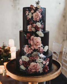 a three tiered black wedding cake with flowers on it