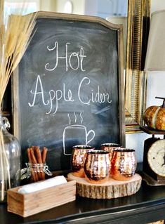 an apple cider is on display in front of a chalkboard with the words hot apple cider written on it