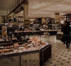 people are shopping in a grocery store filled with meats and other foods on display