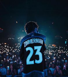 a man standing in front of a crowd with his back turned to the camera, wearing a jersey that reads'zimmerman 23 '