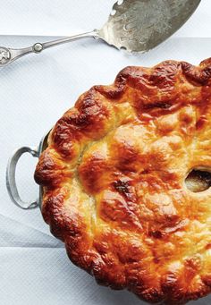 a pie sitting on top of a table next to a fork and knife with a spoon in it