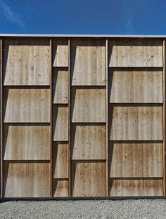 the side of a wooden building with several shelves on each side and blue sky in the background