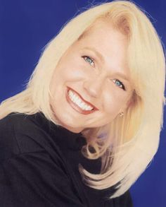 a woman with blonde hair and blue eyes smiles for the camera while wearing a black shirt