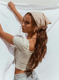 a woman with long brown hair wearing a white shirt and jeans is standing in front of a white sheet