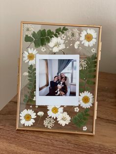 a wooden table topped with a frame filled with flowers