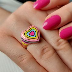 a woman's hand holding a ring with a heart shaped design on the middle