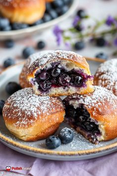 blueberry danish pastries on a plate with powdered sugar and fresh blueberries