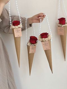 three cones with roses attached to them are hanging on the wall, and one is being held by a woman