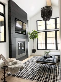 a black and white living room with a tv on the wall, couches, coffee table and rug