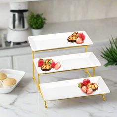 three tiered trays with fruit on them sitting on a marble countertop in a kitchen