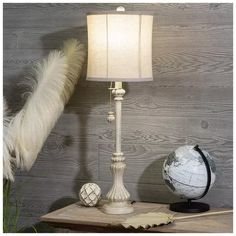 a lamp that is sitting on top of a table next to a globe and feather