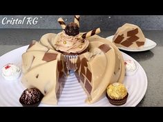 a cupcake decorated with chocolates and candy on a white plate next to other desserts