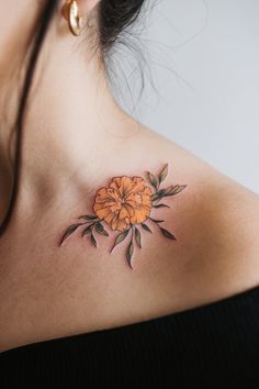 a woman's chest with an orange flower tattoo on it