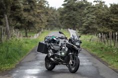 a black motorcycle parked on the side of a road next to some grass and trees