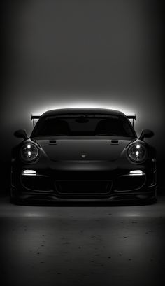 a black and white photo of a car in the dark with its headlights turned on