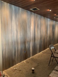 an empty room with two chairs next to a wall that has been painted brown and silver