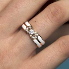 a woman's hand with a gold and white wedding ring on her left finger