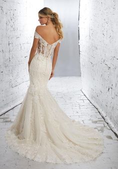 a woman in a white wedding dress is looking down at the back of her gown