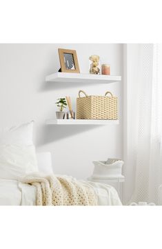 two white shelves with baskets and pictures on them