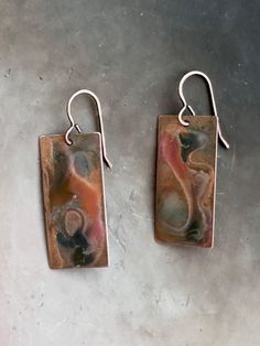 "Raku art-form hand enameled solid copper earrings. Length: 1 1/2\" I use the highest quality USA solid copper. Each copper piece is hand torched, and then enameled by hand with cold enameling in small batches. Through a special process, I mirror each pair of earrings to be complementary. I've been hand-torching metals for over two decades, perfecting the art of natural aging. Adding cold enameling has been a sheer delight. For these earrings, I used a combination of different cold enamels to achieve a raku art-form. The ear wires are copper vermeil over solid brass. USA findings. Each pair has its own qualities and unique beauty. I create these in small batches, so they will be similar to what is in the photographs. I've included a photo of the variances you'll find between each pair of e Artsy Bronze Earrings For Gift, Bronze Artsy Earrings For Gifts, Artisan Rust-colored Earrings As Gift, Artistic Hand Painted Copper Earrings, Artistic Bronze Earrings With Patina, Artistic Copper Earrings With Patina, Artistic Enamel Earrings, Artistic Copper Earrings, Hand Painted Copper Artsy Earrings