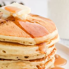 a stack of pancakes covered in syrup on a plate with maple syrup drizzled over the top