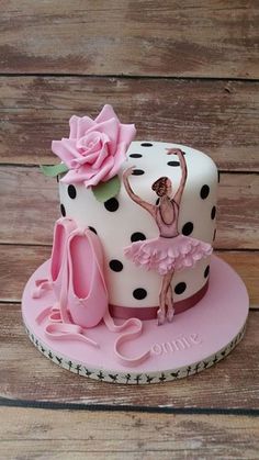 a cake that is decorated with pink and black polka dots, a ballerina on top