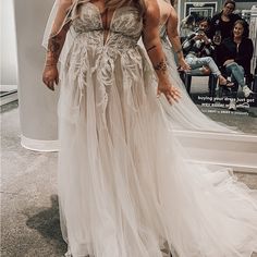 a woman standing in front of a mirror wearing a wedding dress with feathers on it