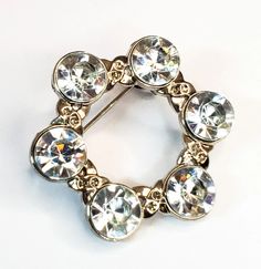 Super bright and shining pave set clear rhinestone brooch. This rhodium plating gives a high contrast compared to the bright color of the rhinestones. Great vintage condition with little to no signs of wear. There is a loop on the back to attach a fob or pendant.  Brooch measures 1 and 1/4th of an inch across and 1 and 3/8ths of an inch tall Formal Silver Jeweled Brooches, Silver Jeweled Brooches For Formal Occasions, Elegant Round Crystal Brooches, Formal Round Rhinestone Brooches, Formal Round Brooches With Rhinestones, Round Formal Brooches With Rhinestones, Round Rhinestone Brooches For Formal Occasions, Anniversary Brooches With Rhinestones, Anniversary Round Rhinestones Brooches