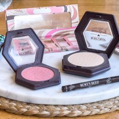 various makeup products sitting on top of a white plate next to a box and brush