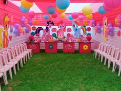 a pink pony themed birthday party with balloons and paper lanterns on the ceiling, tables set up in an open field