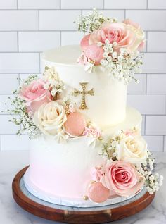 a white cake with pink flowers and a cross on top