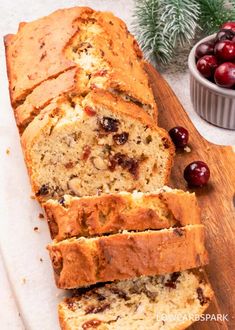 sliced loaf of cranberry bread on a cutting board with cherries in the background