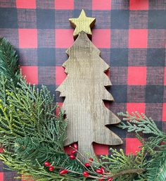 a wooden christmas tree decoration sitting on top of a red and black checkered table cloth