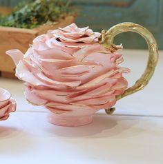 a pink vase sitting on top of a table next to two small cups filled with liquid